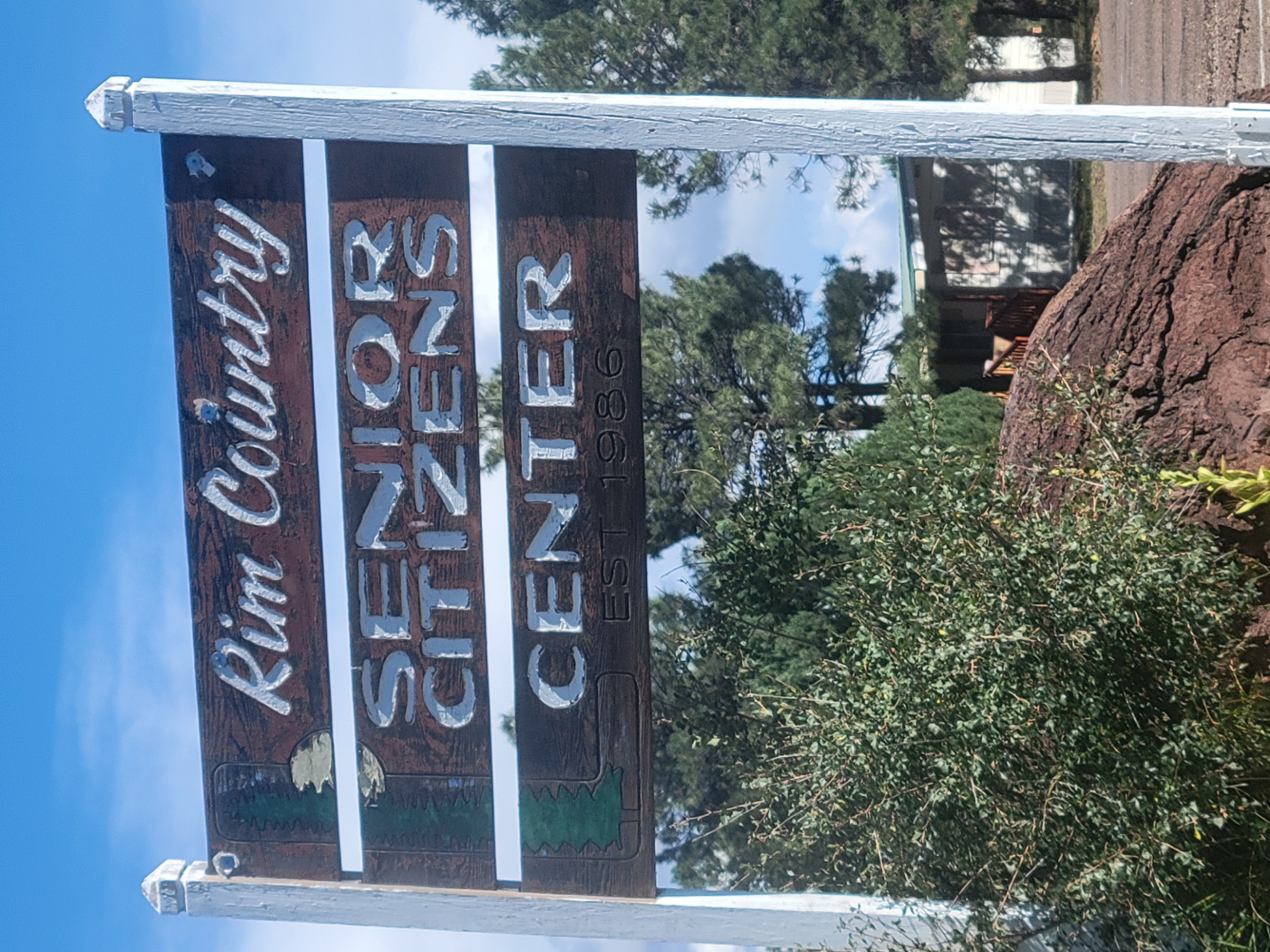 Wooden sign for Rim Country Senior Citizens Center, established 1986, among the pines