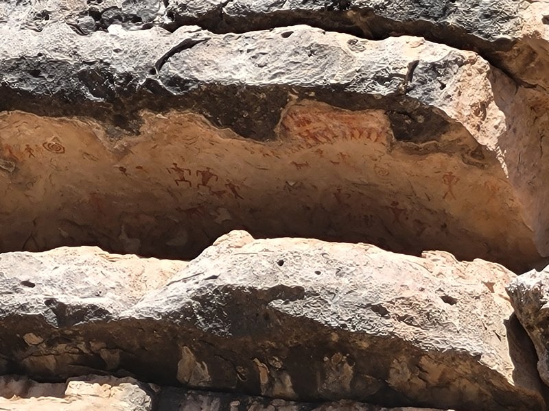 A broad rock overhang shelters small painted markings on the wall beneath it
